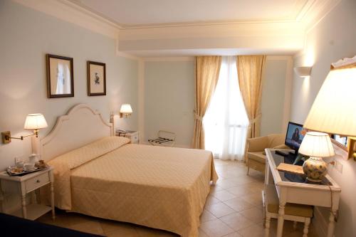 a hotel room with a bed and a chair and a window at Villa Daphne in Giardini Naxos