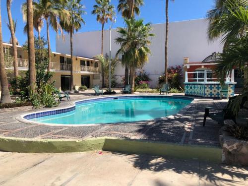 a swimming pool in front of a building with palm trees at Hotel Calafia in La Paz