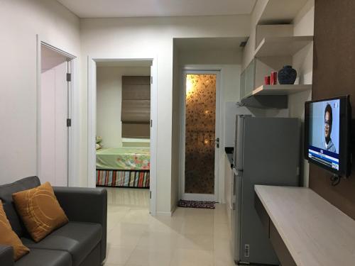 a living room with a couch and a flat screen tv at Apartemen Parahyangan Residence by Rika in Bandung