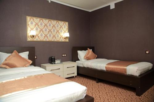 a hotel room with two beds and a picture on the wall at Aska Hotel in Naryn