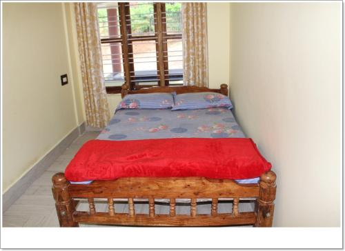 a wooden bed in a room with a window at Lahari Welcomes You in Madikeri