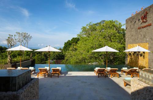 un patio con sillas y sombrillas junto a una piscina en The Tamarind Resort - Nusa Lembongan en Nusa Lembongan