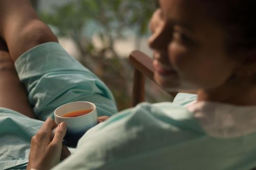 a woman is holding a cup of tea at The Tamarind Resort - Nusa Lembongan in Nusa Lembongan