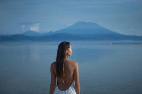 a woman in a white dress standing next to the water at The Tamarind Resort - Nusa Lembongan in Nusa Lembongan