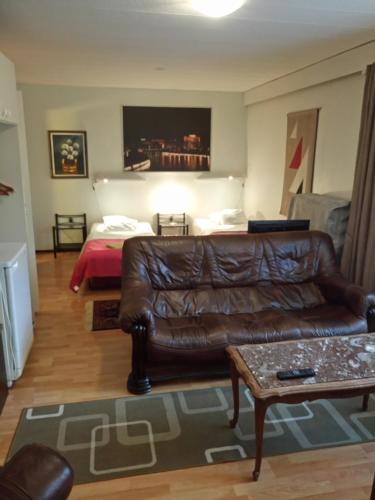 a living room with a leather couch and a bed at Hotel Lamminpää in Tampere