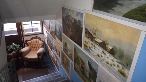 a hallway with paintings on the wall and a chair at Hotel Lamminpää in Tampere