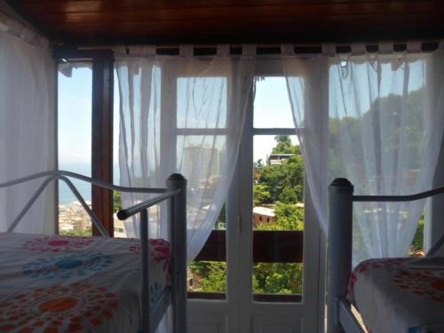 a bedroom with a bed and a large window at Mar da Babilônia Hostel in Rio de Janeiro