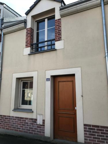 een huis met een bruine deur en twee ramen bij La maison de Julie Albert in Albert