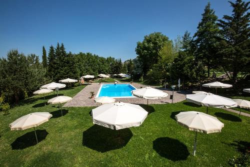 a group of umbrellas in the grass near a pool at Albergo Pian del Bosco in Novafeltria