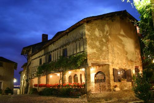 un viejo edificio con flores rojas delante de él en Hostellerie du Vieux Pérouges en Pérouges