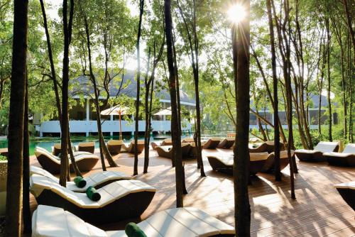 a patio with trees and couches and a pool at Dreamland Maldives Resort in Baa Atoll