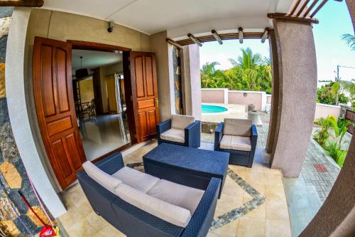 a patio with a couch and chairs and a pool at Villa Chan in Tamarin