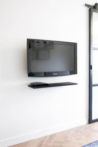 a flat screen tv on a white wall in a living room at Maison Bon Apartments in Den Bosch
