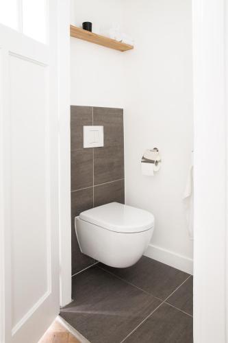 a bathroom with a white toilet in a room at Maison Bon Apartments in Den Bosch