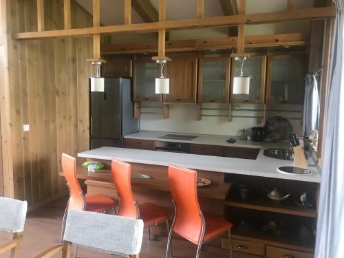 a kitchen with a counter with orange chairs in it at Pirin Golf Villa Emila in Bansko