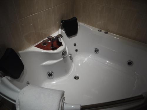 a bathroom with a white bath tub with a sink at Dimple Well Lodge Hotel in Wakefield