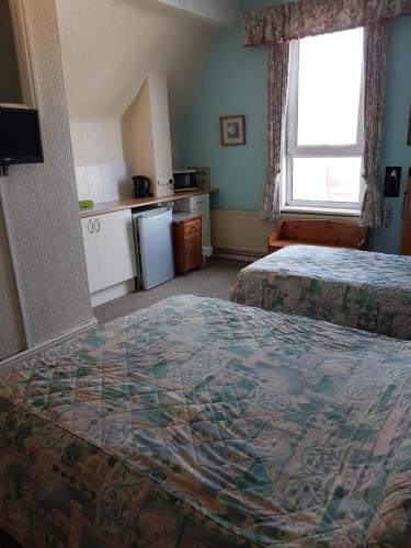 a hotel room with two beds and a kitchen at Cumbria Guest House in Lytham St Annes