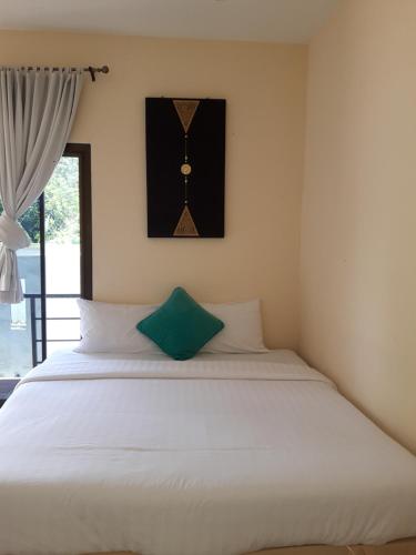 a bedroom with a white bed with a green pillow at Classic home in Bang Tao Beach