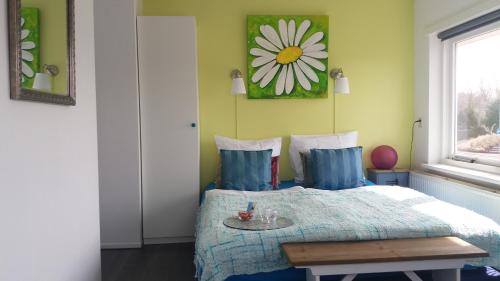 a bedroom with a bed with a flower picture on the wall at Huize de Weijde Blick in Wijk aan Zee
