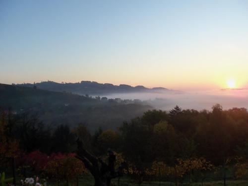 a misty sunrise with the sun rising over a valley at Obstbau und Gästezimmer Stani in Kitzeck im Sausal