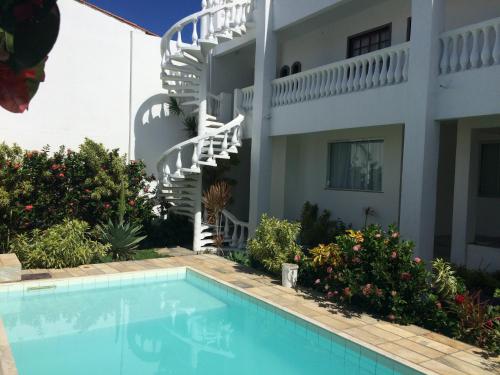 a villa with a swimming pool in front of a house at Casa Dois Corações in Cabo Frio