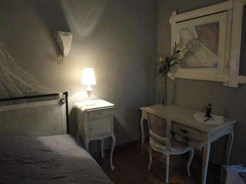 a bedroom with a bed and a desk and a lamp at La Maison d'Hocquincourt in Bléneau