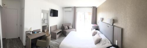 a bedroom with a bed and a desk and a chair at Le Galion Hotel et Restaurant Canet Plage - Logis in Canet-en-Roussillon