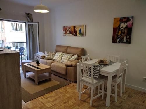 マドリードにあるGran Apartamento Cerca de Atochaのリビングルーム(ソファ、テーブル、椅子付)