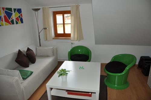 a living room with a couch and two green chairs at Apartmán Šestka in Nová Pec