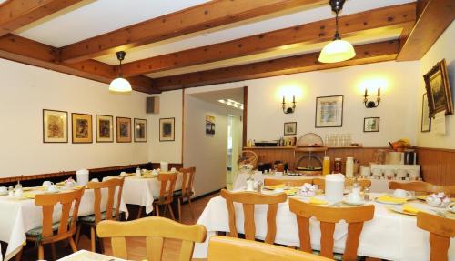 a restaurant with white tables and chairs and wooden ceilings at Waldhotel Unterbach in Düsseldorf