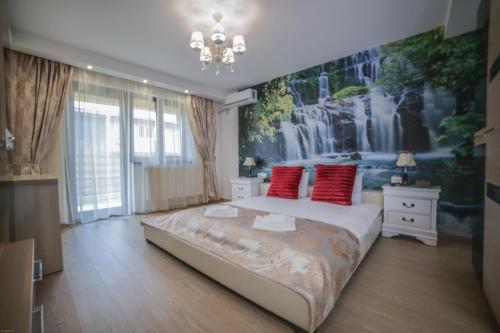 a bedroom with a large bed with red pillows at Studio B in Buftea