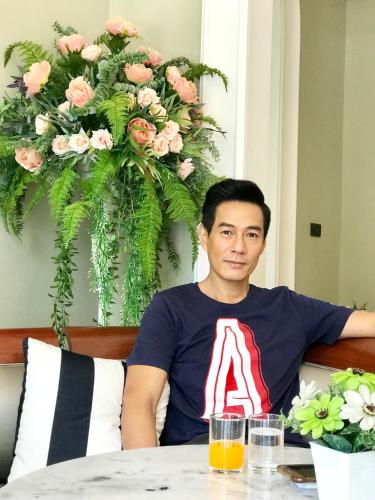 a man sitting at a table in front of a flower arrangement at A Villa Hua Hin Hotel in Hua Hin