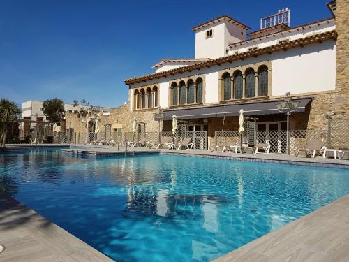a swimming pool in front of a building at Hotel Castell Blanc in Empuriabrava
