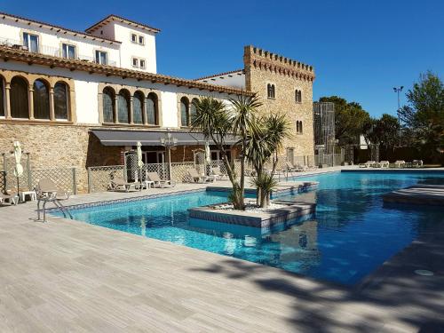 a swimming pool in front of a building at Hotel Castell Blanc in Empuriabrava