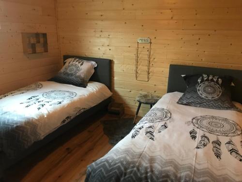 two beds in a room with wooden walls at LA NOALHA INSOLIT' in Lanouaille