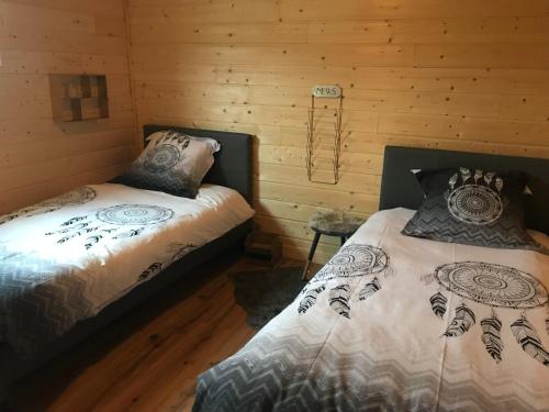 two beds in a room with wooden walls at Arizona Dream in Lanouaille