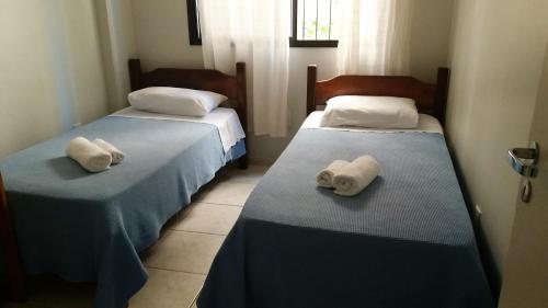 Dos camas en una habitación con toallas. en Ótimo apartamento com wi-fi gratuito, en Guarapari