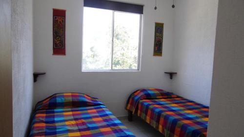 two beds in a room with a window at Relaxing Puertomorelos in Puerto Morelos