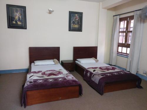 two beds in a room with a window at Om Pension Guest House in Pātan