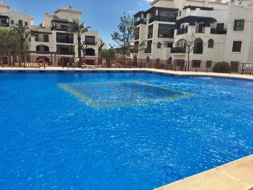 a large blue swimming pool in front of a building at Apartamento Valle Golf Resort in Baños y Mendigo