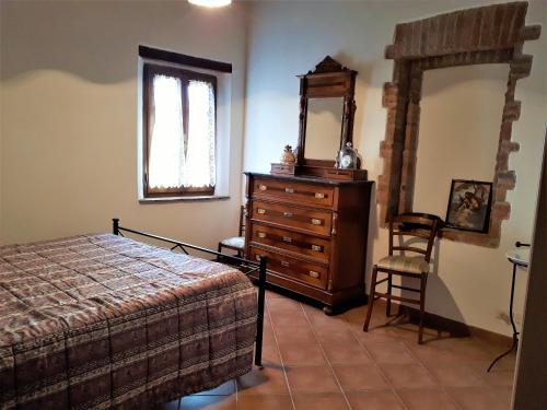Un dormitorio con una cama, una cómoda y un espejo. en Antica Torre "La Casalta", en Petroio