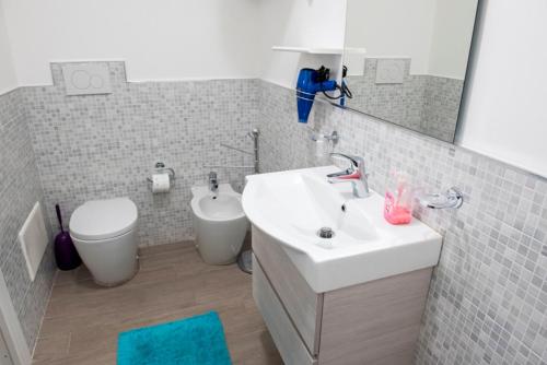Un baño con lavabo, inodoro y espejo. en Miramare 22, en Castelsardo