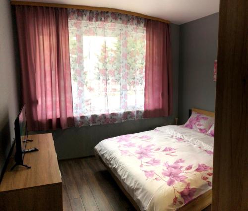 a bedroom with a bed and a window with pink curtains at Radost in Varna City