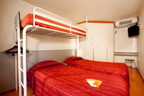 a bedroom with two bunk beds with red sheets at Premiere Classe Lyon Est Aeroport Saint Exupery in Saint-Laurent-de-Mure