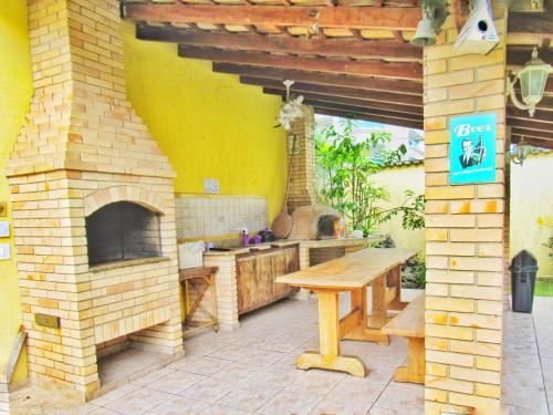 a outdoor kitchen with a brick oven and a wooden table at Pousada Hostel Brazil Backpackers in Guarujá