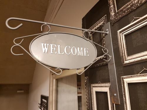 a welcome sign hanging on the side of a building at Hôtel-Restaurant "Chez Carrière" in Aigues-Mortes