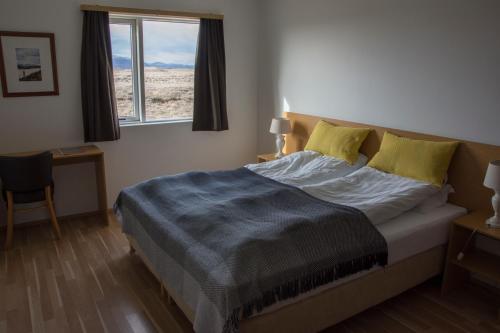 a bedroom with a bed with a blue blanket and a window at Lambastadir Guesthouse in Selfoss