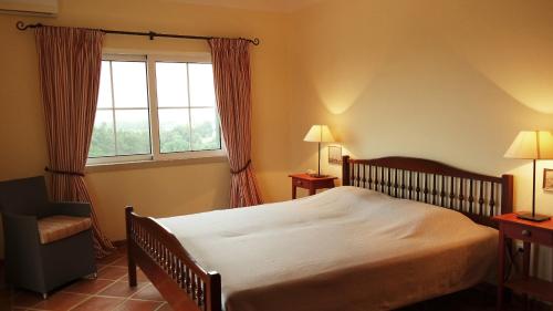 a bedroom with a large bed and a window at Quinta do Sotavento in Moncarapacho