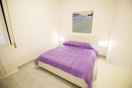 a bedroom with a purple bed with a painting on the wall at ArtHouse in San Vito lo Capo
