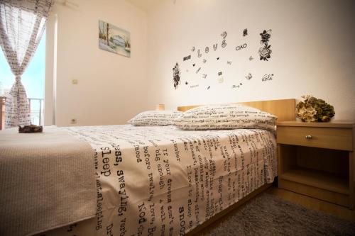 a bedroom with a bed with writing on the wall at Apartment & Rooms Marigold in Baška Voda
